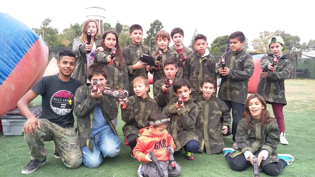 Grupo de chicos con chaquetas de combate y marcadoras láser en el campo